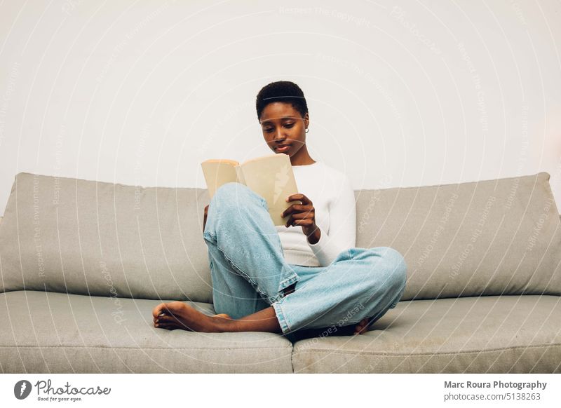 schwarze Frau lesend auf einem Sofa Erwachsener Hintergrund schön Buch Kaukasier Kaffee bequem Liege trinken Bildung Mädchen Glück Hobby Beteiligung heimwärts