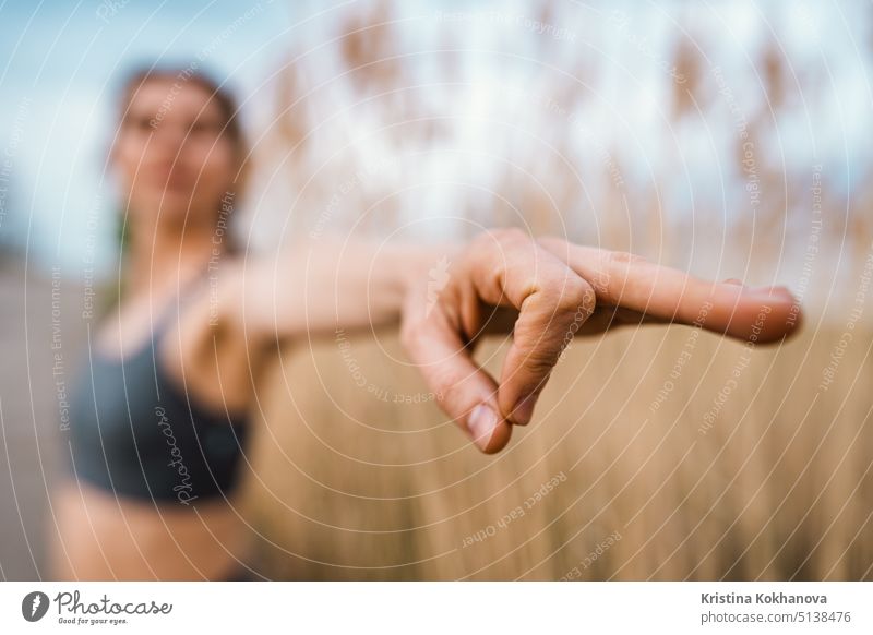 Europäische Frau macht Yoga-Übung auf Schilf natürlichen Hintergrund. Konzentrierte Mädchen Training im Sommer im Freien. Pastellfarben, Einheit mit der Natur, Gleichgewicht, Lifestyle-Konzept.