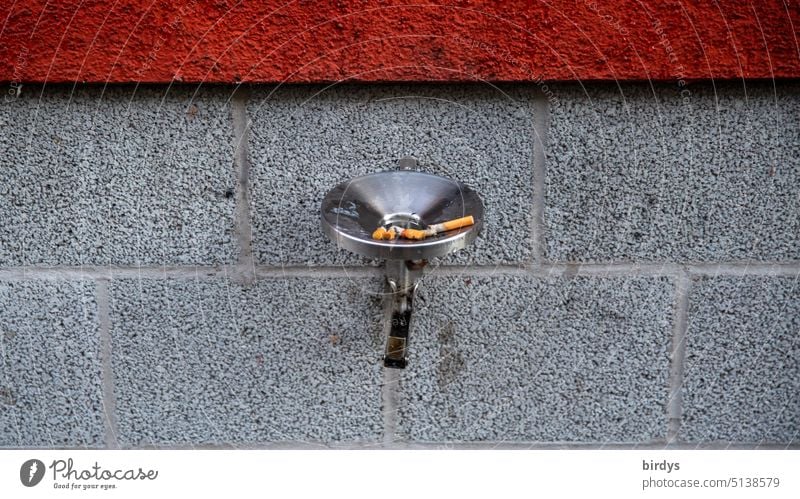 Aschenbecher mit Zigarettenkippen an der Außenwand eines Hauses Rauchen Zigarettenstummel gesundheitsschädlich Nikotin Filterzigarette Gesundheitsrisiko