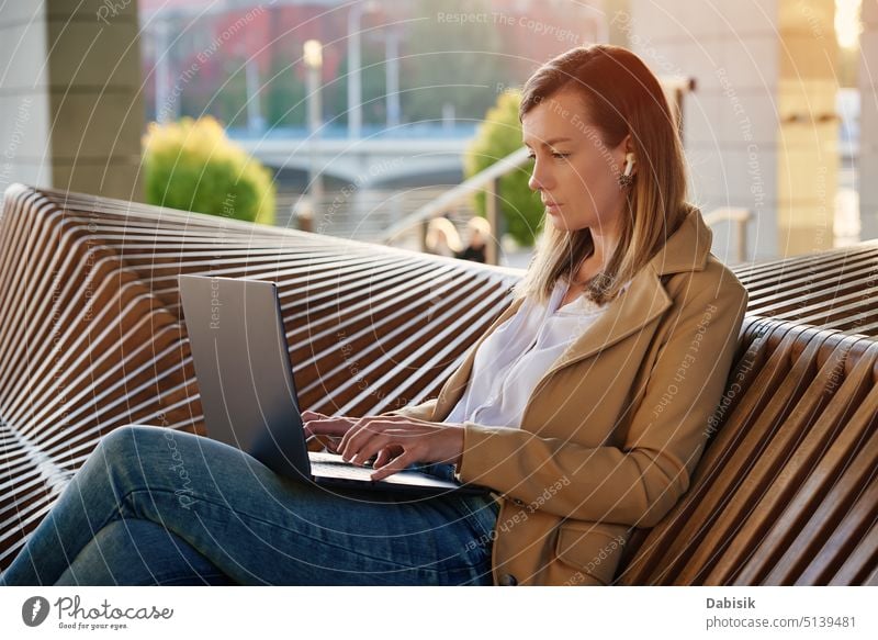 Frau sitzt mit einem Laptop auf einer Treppe im Freien bei Sonnenuntergang. Computer arbeiten freiberuflich online Bank abgelegen Gebäude e Lernen Netzwerk