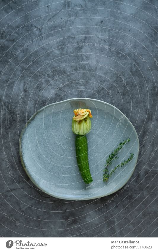Zucchiniblüte auf Teller auf Steinhintergrund. Vertikales Foto. Blume Gemüse vertikales Foto Draufsicht steinerner Hintergrund Steineffekt grün Gesundheit Ernte