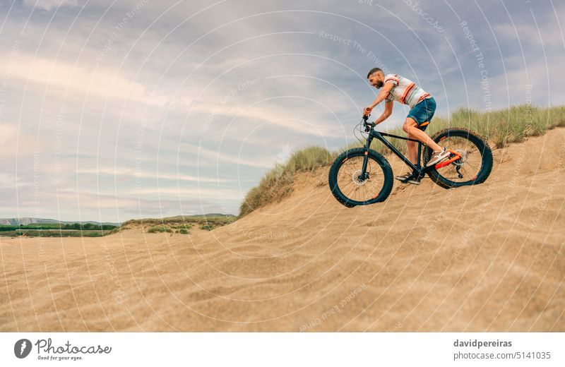 Mann fährt mit einem Fatbike durch die Stranddünen jung Reiten Düne Textfreiraum untergehend Person Fahrrad Lifestyle Zyklus Fett aktiv Radfahrer Radfahren