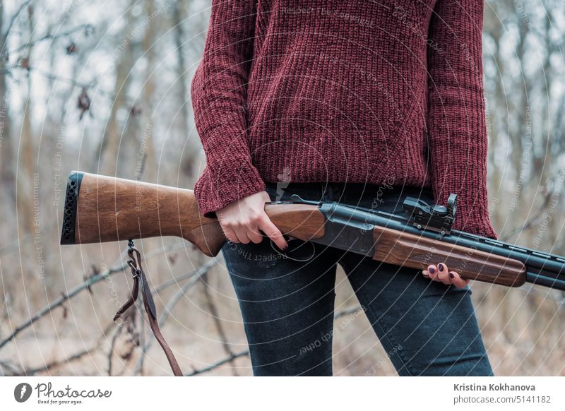 Jägerin in weinroter warmer Kleidung mit Gewehr. Mädchen auf der Jagd im Wald hält ihr Gewehr in Großaufnahme. Aktivität Erwachsener zielen Ziel Adel Herbst