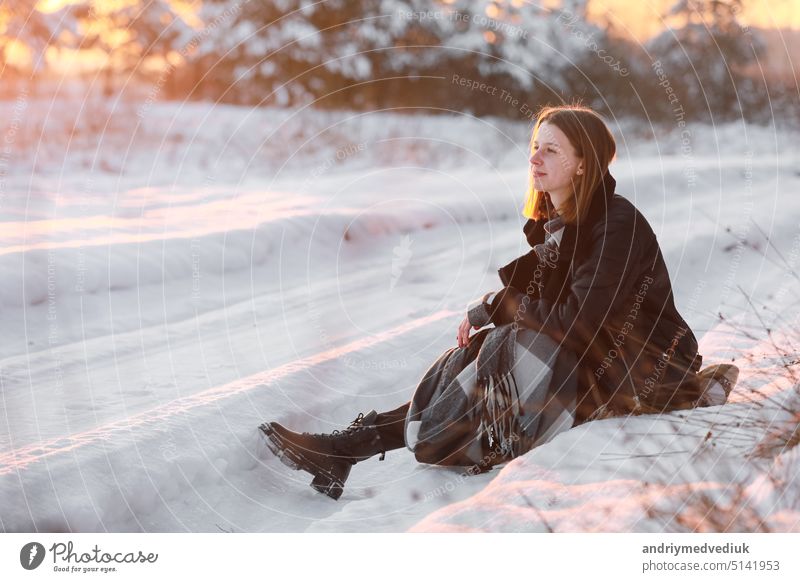 Junge schöne Frau mit kurzen Haaren, in kariertem Schal, die im verschneiten Wald bei Sonnenuntergang spazieren geht. Weihnachtsurlaub. Schneetag Spaß Winter