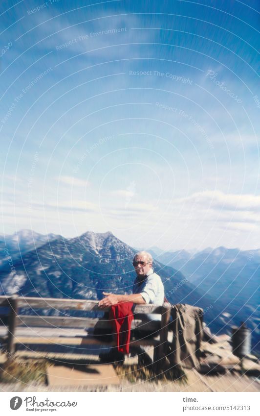 naturverbunden | Wanderpause Mann Berge Bergkette Sitzbank Wandern Sommer Panorama Reisen schönes Wetter Himmel sitzen 1970er blick in die Kamera schauen