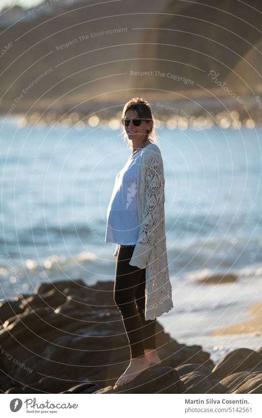 Junge schwangere Frau an der Küste an einem sonnigen Tag Unterleib Erwachsener Vorfreude Strand schön Schönheit Bauch Bikini Familie Spaß Mädchen Glück