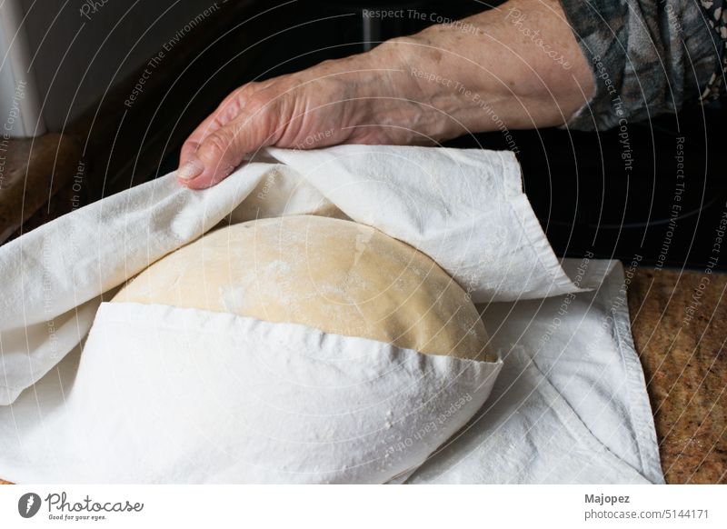 Unerkennbarer menschlicher Hanad, der den Kaskadenteig während des Aufgehens kontrolliert roh Gebäck alte Frau Hintergrund Bäckerei Brot braun Kaukasier