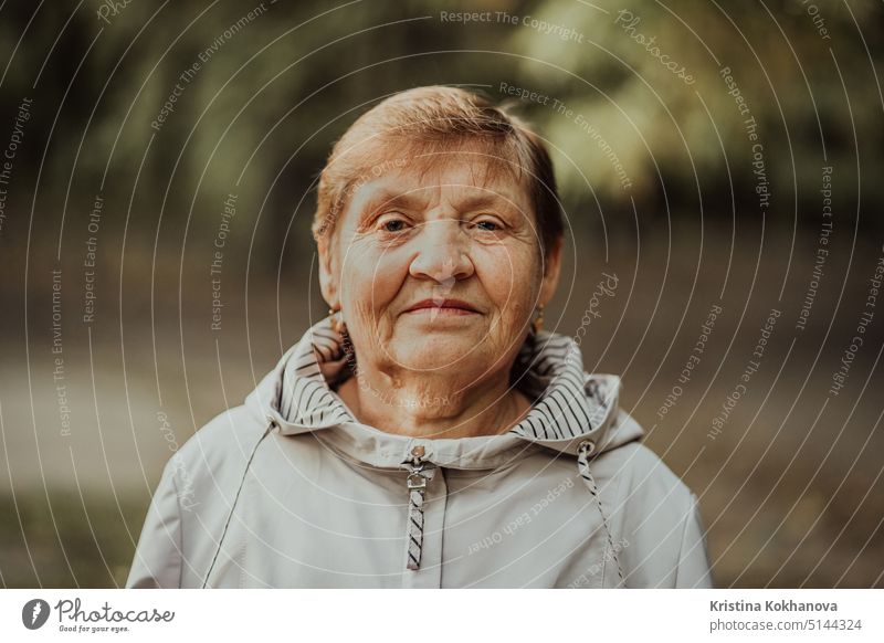 Schönes Porträt der lächelnden alten Frau im Herbst Park. Kaukasische Großmutter schaut in die Kamera. Lebensalter Holunderbusch älter gut menschlich reif
