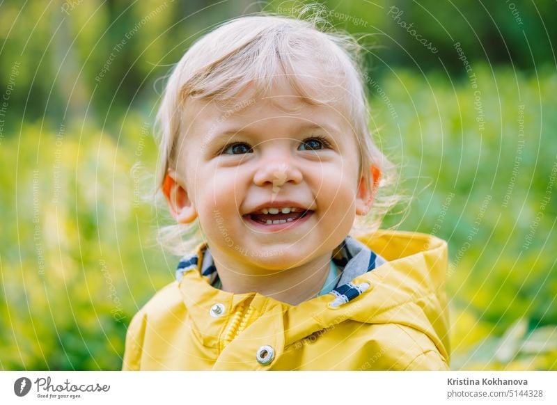 Porträt eines niedlichen kleinen Jungen im gelben Regenmantel. Kind lächelnd. Liebe, Pflege, Bindung, Familie, Kinder Konzept. Person Kindheit Freude Lächeln