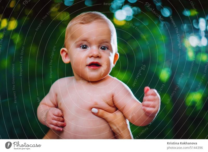 Hübscher kleiner Junge schaut zur Kamera und lächelt auf grünem Waldhintergrund. Baby Kind niedlich schön Gesicht Kindheit spielen Auge Person heiter Spielen