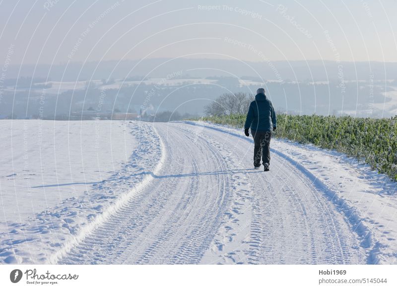 Wanderin läuft im Winter bei Sonnenschein durch das Heckengäu bei Weissach sonnig Wandern aktiv Horizont Himmel Landschaft Frost Schnee Sportlich gehen