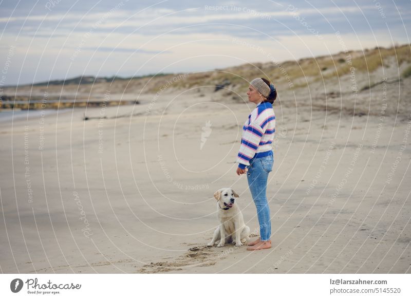 Brünette Frau mittleren Alters am leeren Strand mit ihrem Labrador-Retriever-Hund Winter Profil Textfreiraum Herbst überrascht nass feucht Küste Ufer