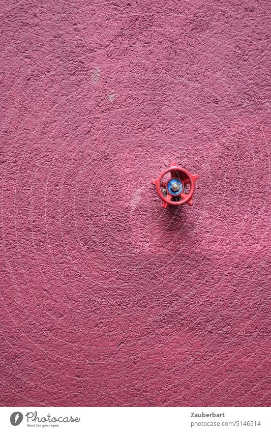 Rotes Rad eines Ventils für Wasser auf Wand mit grobem Putz in altrosa als Hintergrund oder Akzent rot rauh rosarot allein Technik Detail Mauer Fassade drehen