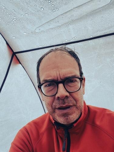 Wanderer bei Kälte und Regen, aber noch hält das Zelt Mann Bestager durchregnen nass Tropfen Nässe Dreitagebart unrasiert rot Abenteuer outdoor draußen drinnen