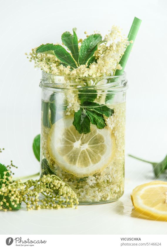 Gesunde Holunderblütenlimonade im Glas mit Zitrone auf weißem Hintergrund Gesundheit Limonade weißer Hintergrund aufgegossenes Wasser grün Bestandteil