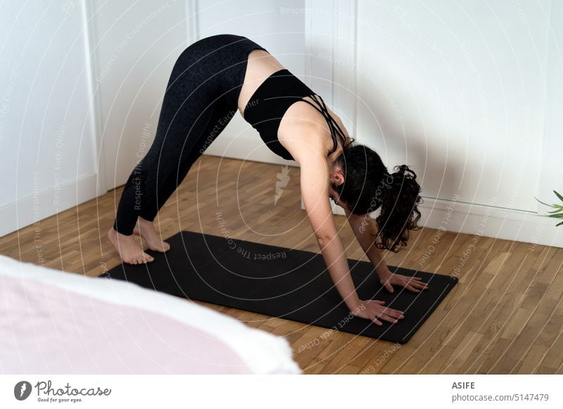 Junge Frau beim Üben einer Yoga-Asana in ihrem Schlafzimmer. Übung heimwärts jung Sport adho echte Menschen offen mukha svanasana abwärts Pose Unterlage Stock