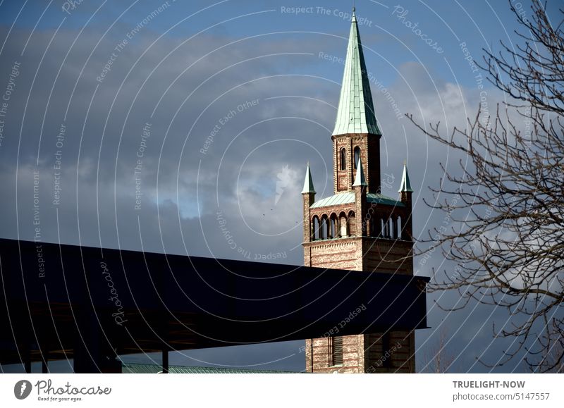 Kunst und Kirche: Das mächtige dunkle Stahldach der sanierten Neuen Nationalgalerie schiebt sich vor den neoromanischen Turm der St. Matthaeus Kirche unter leicht bewölkt winterlichem Himmel von Berlin