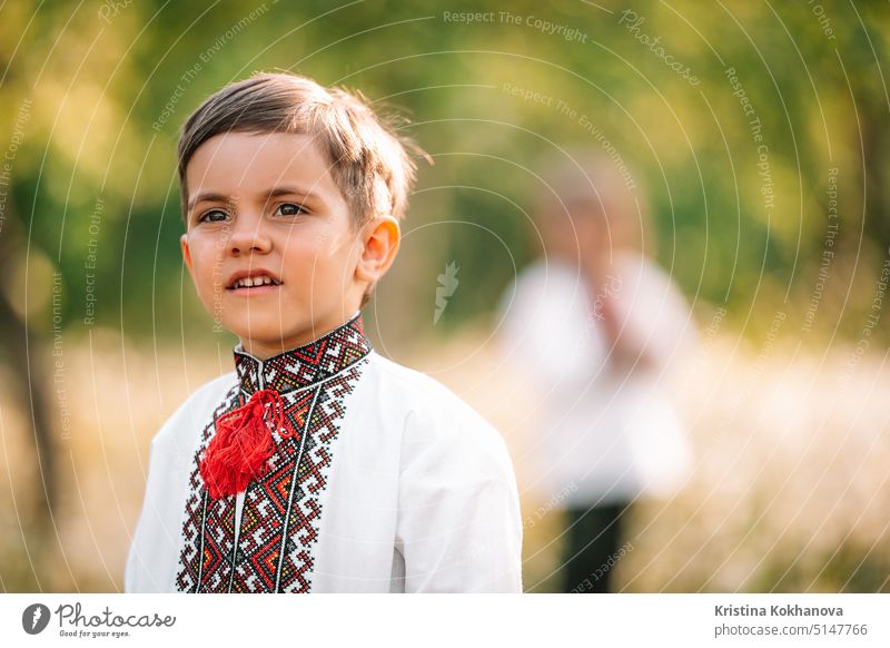 Niedliches Porträt eines kleinen ukrainischen Jungen im Frühlingsgarten. Kind in traditioneller Stickerei vyshyvanka Shirt. Ukraine, Freiheit, Nationaltracht, Sieg im Krieg, glückliche Kindheit und Zukunft Konzept,