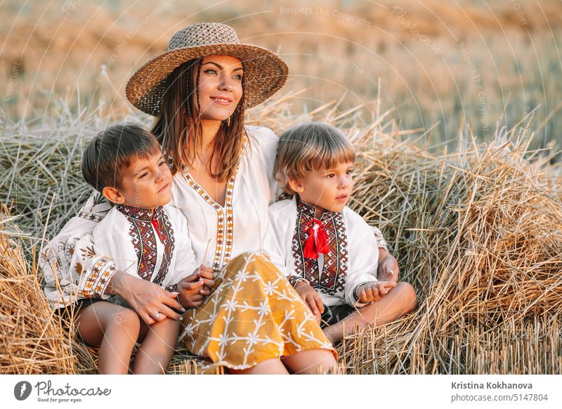 Ukrainische Jungen und Mutter sitzen nach der Ernte auf einem Weizenfeld zusammen. Familie, Freunde halten sich an den Händen. Kinder sind unsere Zukunft. Glückliche Kindheit.