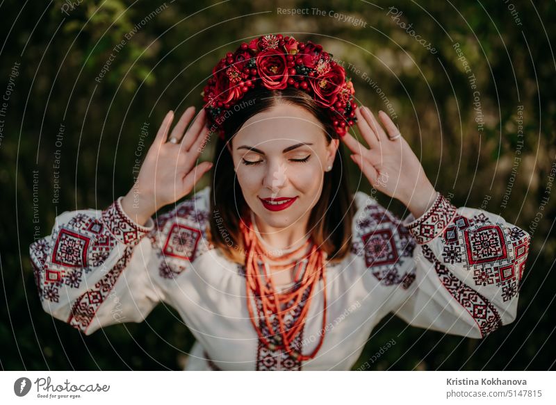 Attraktive ukrainische Frau in traditioneller Stickerei vyshyvanka Kleid, alte Korallen Perlen und roten Blumen Kranz. Ukraine, Freiheit, Kultur, Nationaltracht, Sieg im Krieg.