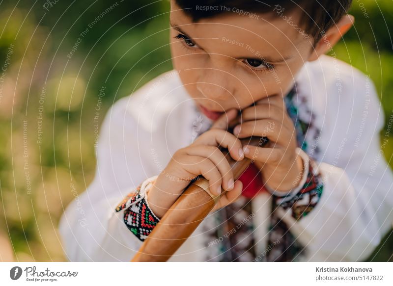 Porträt des kleinen Jungen mit Holzblasinstrumenten Holzflöte - ukrainische Sopilka. Konzept der Volksmusik. Musikinstrument. Kind in traditionellen gestickten Hemd - Vyshyvanka.