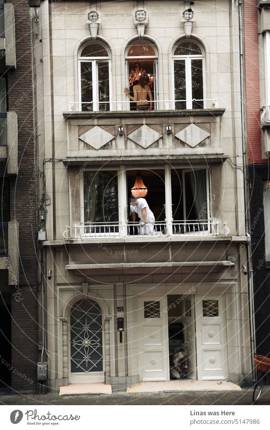 Es ist ein belebtes Gebäude in der Altstadt. Eine barbusige Frau auf dem dritten Balkon. Unten arbeiten zwei Maler. Eine filmische Aufnahme von der Straße in Antwerpen, Belgien.
