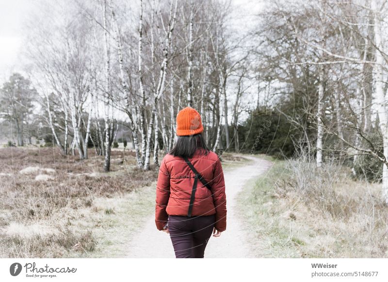 Die junge Frau ist für die Wanderung durch die winterliche Heide warm angezogen wandern Spaziergang spazieren Winter Weg laufen Pfad Landschaft Natur