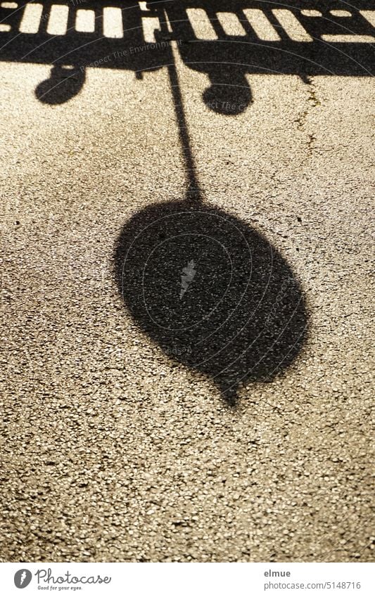 farbreduziert I Schatten eines runden Verkehrsschildes und einer Absperrbake auf Asphalt / Baustelle Absperrung Bake Straßenbauarbeiten Schattenspiel