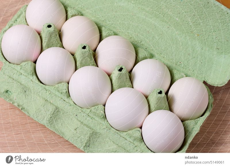 Frische weiße Volleier in grüner Papierverpackung auf einem Holztisch Kasten Ei Eierschale Paket Verpackung Bauernhof Lebensmittel zerbrechlich frisch