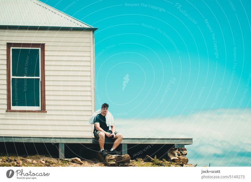 eine wohlverdiente Pause am Ruby Hunt's Cottage Haus Junger Mann Fenster traditionell sitzen Himmel Wolken Dach Holzwand Fassade Plattform Australien Tasmanien