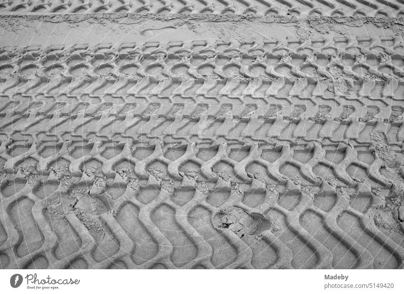 Grobe Reifenspuren im Sand am Strand in Knokke-Heist an der Nordsee bei Brügge in Westflandern in Belgien, fotografiert in klassischem Schwarzweiß muster
