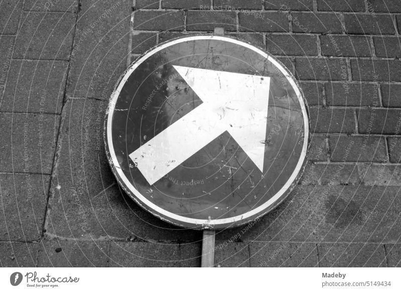Umgestürztes Verkehrszeichen mit Pfeil auf dem Gehweg an einer Baustelle in Knokke-Heist an der Nordsee in Westflandern in Belgien in klassischem Schwarzweiß