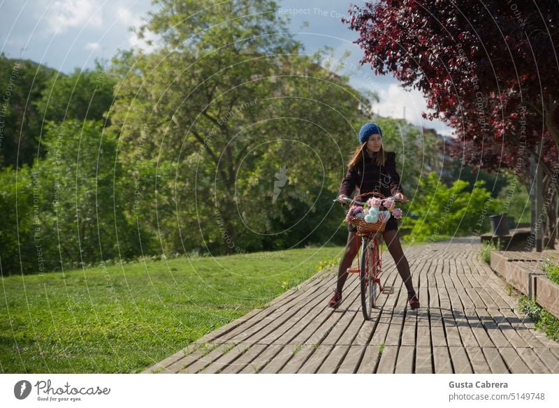 Mädchen geht mit ihrem roten Fahrrad und Blumen einen Holzweg entlang. Frau Spaziergang Außenaufnahme Erholung Farbfoto Ferien & Urlaub & Reisen Tourismus