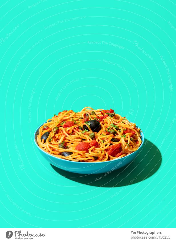 Spaghetti puttanesca Schüssel minimalistisch auf einem grünen Hintergrund oben blau Schalen & Schüsseln hell Kapriolen Kohlenhydrate Nahaufnahme Farbe gekocht