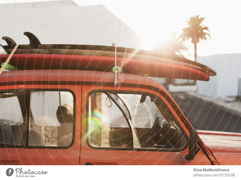 Ein Stapel von Surfbrettern auf einem Retro-Autodach mit Sonne scheint. Sommer und Surfen Hintergrund Tapete. Vintage-Autodach mit sandigen Surfbretter auf sie gestapelt. Urlaubsmodus. Easy entspannten Lebensstil, leben in den Moment Konzept.