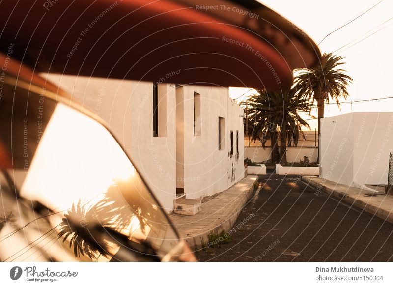 Ein Stapel von Surfbrettern auf einem Retro-Autodach mit Sonnenschein bei Sonnenuntergang mit Palmen. Sommer und Surfen Hintergrund Tapete. Vintage-Autodach mit sandigen Surfbretter auf sie gestapelt. Urlaubsmodus. Easy entspannten Lebensstil, leben in den Moment Konzept.