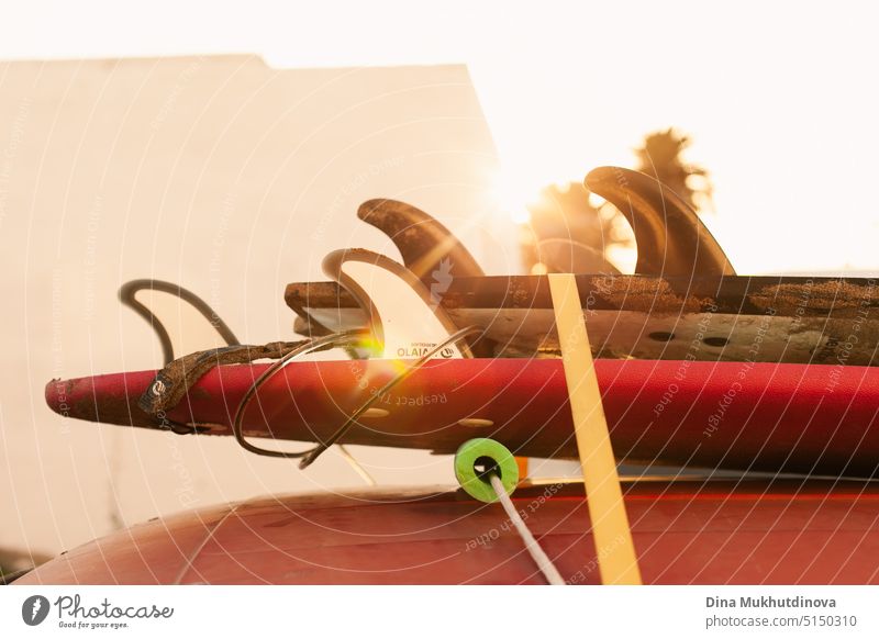 Surfbretter auf dem Dach eines roten Retro-Autos bei Sonnenuntergang. Surfen Lifestyle Hintergrund und Tapete. Sandy Surfbretter auf dem Dach des Oldtimer horizontale Kulisse.