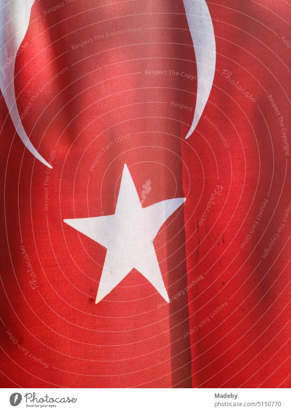 Rote türkische Fahne mit weißem Stern im Sommer bei Sonnenschein an einem Hauseingang in Inkumu am Schwarzen Meer in der Provinz Bartin in der Türkei Knallrot