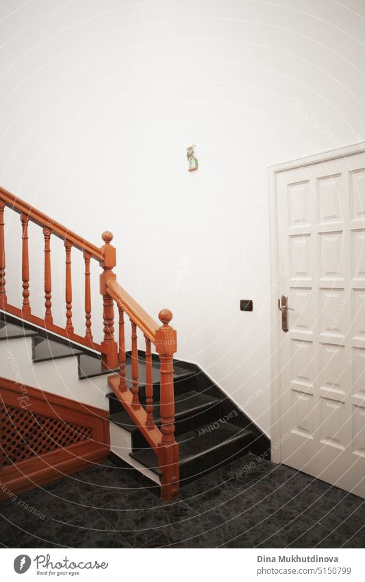 Eine Holztreppe zu Hause vertikale Interieur Hintergrund. Minimale Innenarchitektur mit einer weißen Tür und braunen Treppe mit Kopie Raum. Appartement
