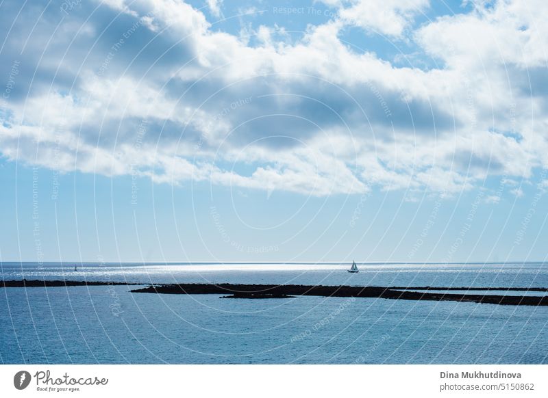 Seelandschaft und Wolkenlandschaft in blauer Farbpalette. Ruhiges Meer an einem sonnigen Tag mit Wolken horizontalen Landschaft Hintergrund.  Entfernte Bootssilhouette im Ozean.