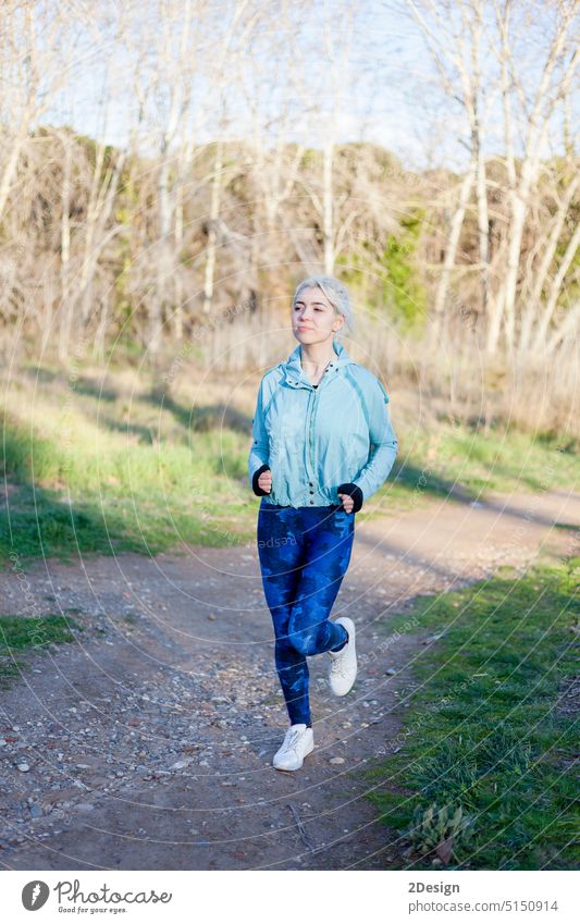 Fitte, gesunde junge Frau beim Joggen auf einer Landstraße rennen Sport aktiv Fußweg passen Vitalität Textfreiraum Aktivität Gesundheit Lifestyle im Freien