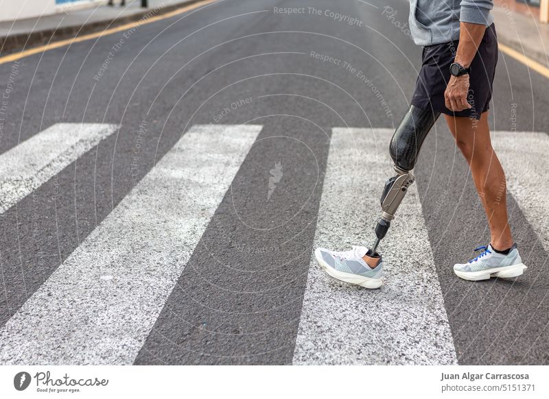Behinderter männlicher Sportler beim Überqueren der Straße Amputierte Spaziergang Zebrastreifen Training Fitness urban Fußgänger Verkehr Turnschuh