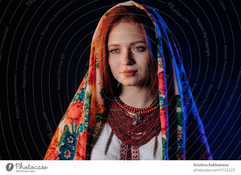 Charmante rothaarige Frau in traditionellem ukrainischem Taschentuch, Halskette und bestickter Bluse auf schwarzem Hintergrund. Ukraine, Stil, Folk, ethnische Kultur.