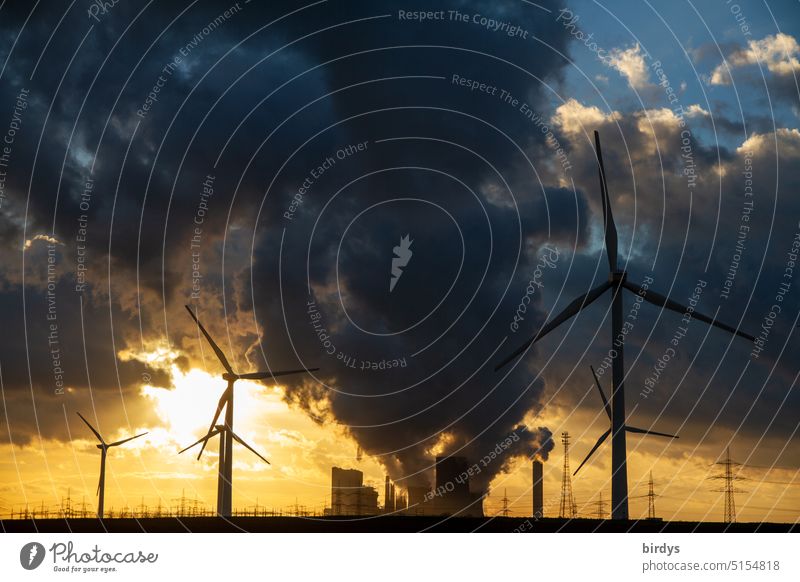 Kohleausstieg. Braunkohlenkraftwerk mit Windrädern im Vordergrund bei Sonnenuntergang Klimakrise Klimawandel CO2-Ausstoß Fossile Energie Emissionshandel
