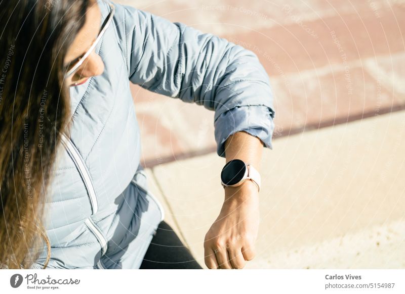 lateinamerikanische Frau mit langen Haaren schaut auf eine Smartwatch Zugänglichkeit Arme Geschäftsfrau beschäftigt Überprüfung Uhr Textfreiraum Frist Gerät