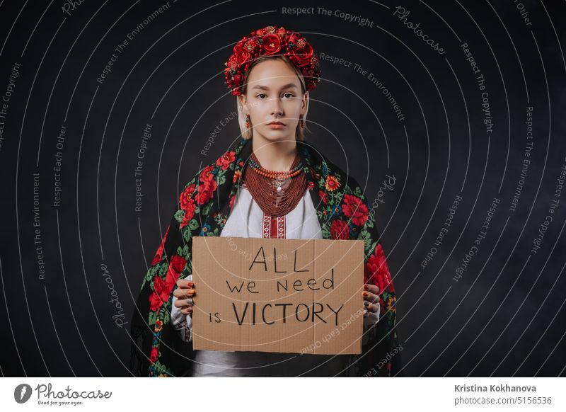 Ukrainische Frau mit Karton All we need is victory auf schwarzem Hintergrund. Ukraine protestieren Ukrainer Kundgebung Fahne Politik Freiheit politisch stoppen