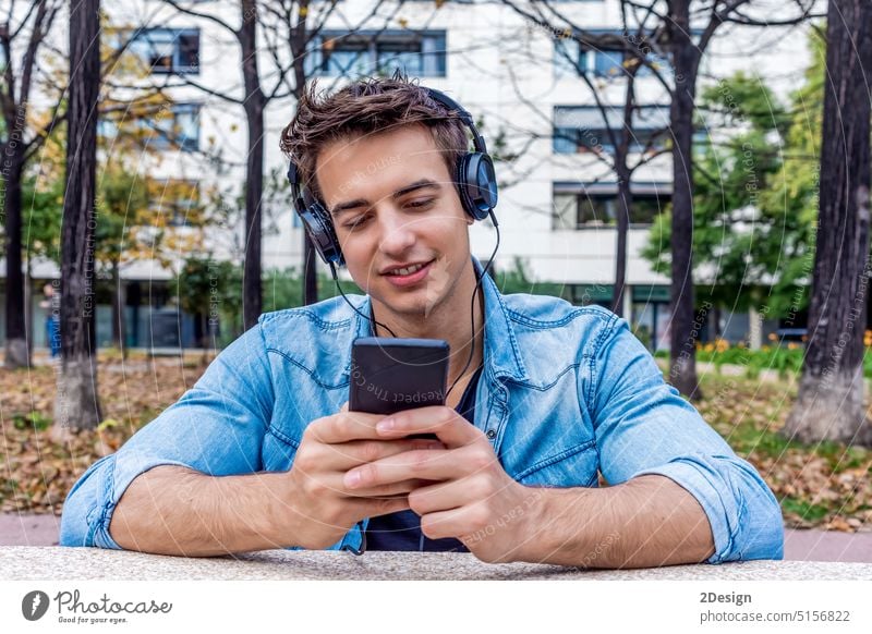 Mann hört Musik von einem Smartphone im Stadthintergrund Technik & Technologie Person Kopfhörer benutzend männlich Mobile Telefon Lifestyle Großstadt im Freien