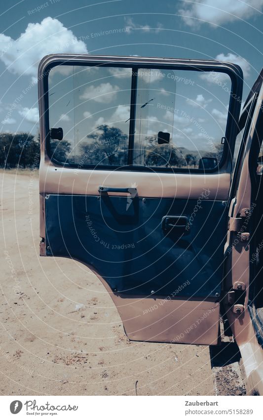 Geöffnete Tür eines Geländewagens auf Sandboden in der Serengeti bei Sonnenschein Safari Auto fahren robust gelände geländegängig Allrad Wüste Abenteuer PKW