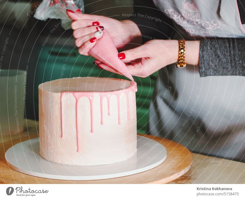Unerkennbare Frau, die Mousse-Glasur-Torte mit Rose und Macarons verziert Kuchen dekorierend Dekoration & Verzierung 30s backen Kaukasier Feier Nahaufnahme