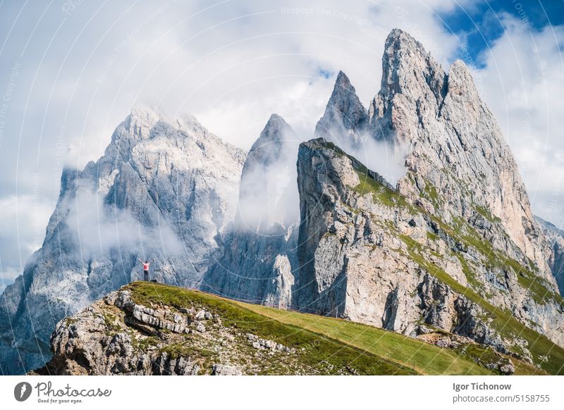 Ein Mann hebt die Hände vor den epischen Gipfeln Furchetta und Sass Rigais in Seceda, Dolomiten, Geislergruppe, Südtirol, Italien, Europa. Reisen Urlaub Konzept